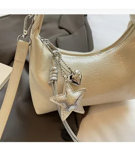 Détail du sac seau crème en cuir verni plissé avec breloques étoile et coeur