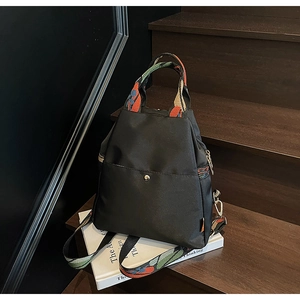 Détail du sac à dos en nylon noir avec des bretelles tissées colorées sur un escalier