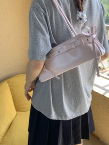 Light pink baguette shoulder bag with leather bow decoration and metallic eyelets