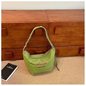 Close-up of light green hobo bag with scrunchie shoulder strap and pleated nylon texture