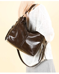 Modella che indossa una borsa a secchiello marrone scuro con eleganti cuciture verticali