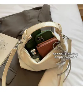 Détail du sac seau en cuir verni crème montrant la grande capacité intérieure de rangement