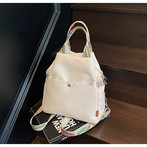 Détail du sac en nylon blanc montrant la bandoulière tissée colorée et la boucle métallique