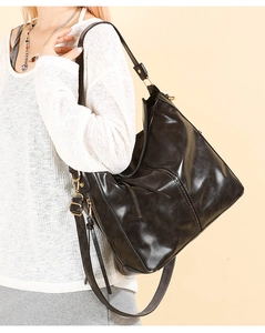 Dettaglio della grande borsa tote nera in pelle lucida con finiture in metallo dorato