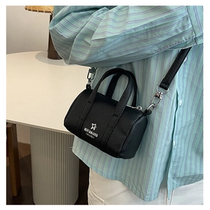 Mini black barrel crossbody bag in pebble leather with adjustable silver buckle strap