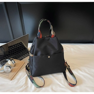 Détail du sac à dos en nylon noir étanche avec sangles brodées ethniques et poches de côté
