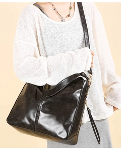 Dettaglio della borsa a secchiello nera con texture in pelle vintage e hardware dorato