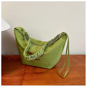 Detail of matcha green pleated shoulder bag showing nylon texture and red printed logo