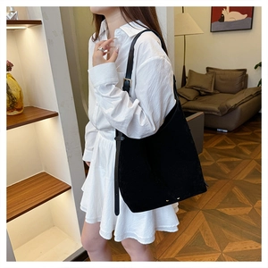 Detail of minimalist black suede tote bag featuring a premium gold adjustable buckle strap