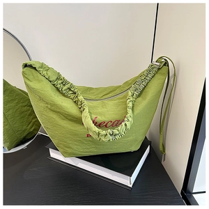Detail of green nylon hobo bag with pleated handle and red artistic lettering