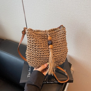Borsa a secchiello in paglia intrecciata a mano marrone con nappe e tracolla pelle