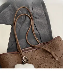 Dettaglio ravvicinato della borsa shopper marrone scuro con motivi a rilievo e ciondolo morbido