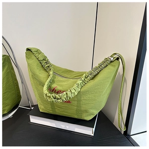 Close-up of avocado green nylon hobo bag with ruched strap and red text detail