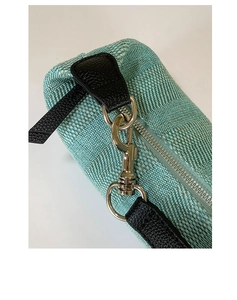 Close-up of mint green woven texture with black leather trim and silver metal hardware