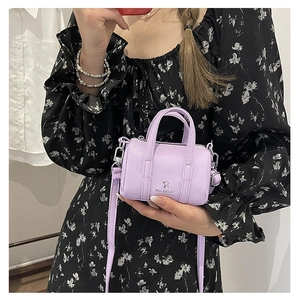 Detailed close-up of a purple mini Boston bag with pebbled leather and thin strap