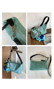 Detail of mint green woven handbag with leather strap and blue elephant charm decoration