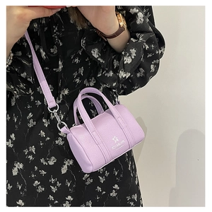 Detail of lavender textured leather mini barrel bag with logo and thin shoulder strap