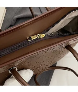 Dettaglio della cerniera dorata e del motivo goffrato su una borsa tote marrone