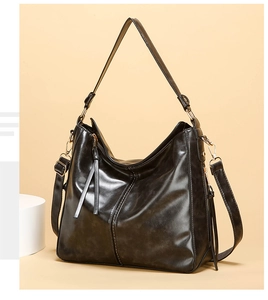 Dettaglio di una borsa hobo nera con doppie nappe e finiture metalliche dorate