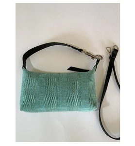 Flat lay of woven mint green shoulder bag with black leather strap and silver hardware