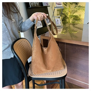 Detail of soft brown suede hobo bag with adjustable strap in a cozy interior setting