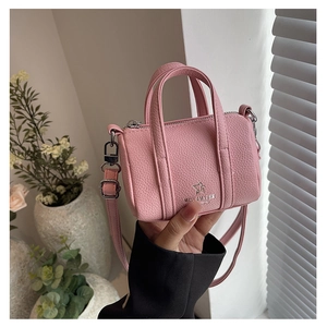 Detail of pink mini pillow bag in lychee leather featuring embossed logo and top handles