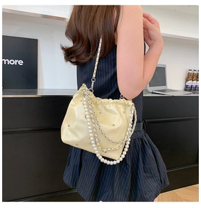 Détail du sac seau matelassé crème avec bandoulière perle et chaîne sur mannequin