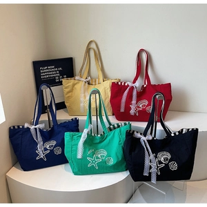 Détail de sacs cabas en toile rayés colorés avec motifs d'étoiles de mer et nœuds en dentelle