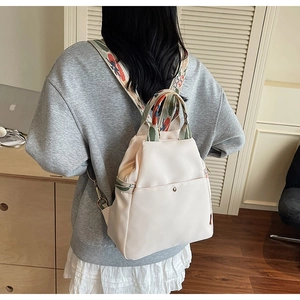 Détail du sac à dos blanc crème avec broderie florale vintage sur les poignées et bretelles
