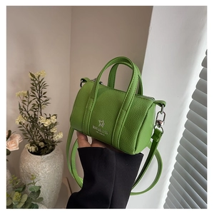 Close-up of grass green mini cylinder bag with litchi grain texture and silver logo
