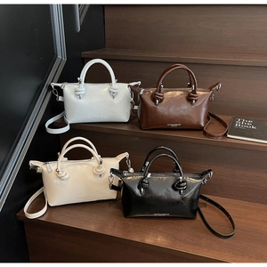 Detail of four patent leather boston bags in white brown and black on wooden stairs