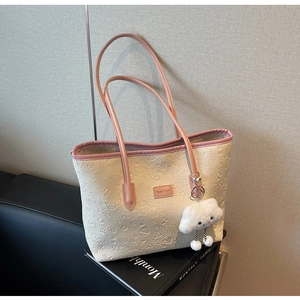Dettaglio della borsa tote beige con manici rosa e motivi a nuvola di cartoni animati in rilievo