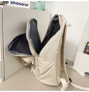 Detail view of the cream nylon backpack with multiple compartments and gray lining