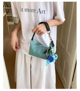 Detail of teal woven crossbody bag with blue elephant charms and black handle