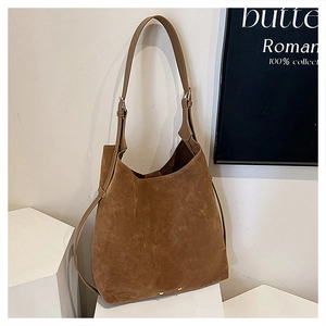 Detailed close-up of brown matte suede bucket bag with gold rivets on geometric stand