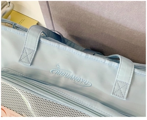 Detail of light blue tote bag featuring brand embroidery and white mesh fabric texture