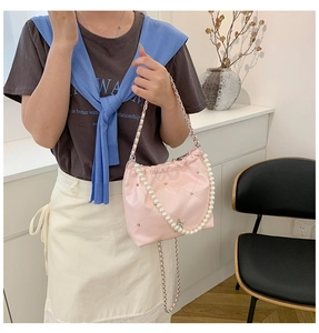 Détail du sac seau rose matelassé avec poignée en perles et bandoulière en chaîne