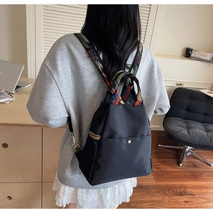 Détail du sac à dos en nylon noir avec bretelles brodées de motifs ethniques colorés