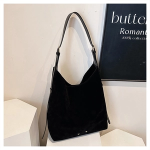 Detailed macro view of black matte suede texture and small golden rivets on the hobo bag