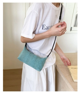 Detail of mint green woven crossbody bag with a slim black shoulder strap for summer