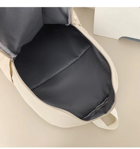 Close-up of a cream backpack with spacious main compartment and dark interior lining