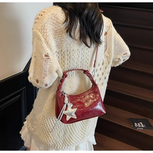 Détail du sac seau croissant rouge brillant avec un pendentif en forme d'étoile argentée