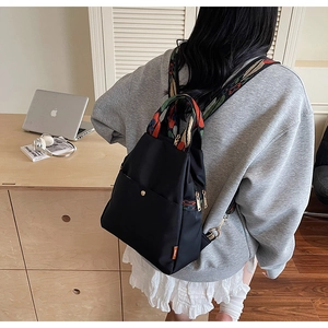 Détail d'un sac à dos en nylon noir avec sangles jacquard ethniques et boucles en métal doré