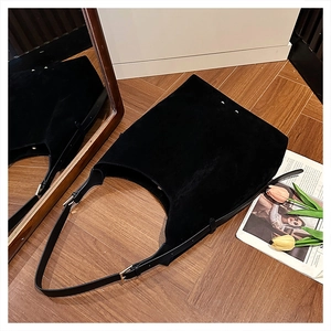 Close-up of black suede hobo bag with gold hardware buckle and leather shoulder strap