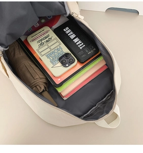 Top view of spacious cream canvas backpack interior holding a tablet and daily essentials