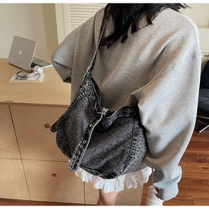 Detail of vintage grey denim hobo bag with eyelet accents worn by model on shoulder