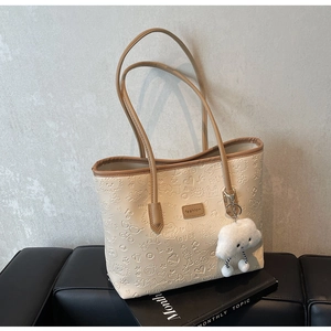 Dettaglio della borsa tote beige crema con trame a rilievo e ciondolo a nuvola soffice