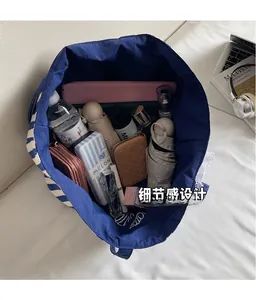 Détail de l'intérieur du grand sac fourre-tout rayé montrant sa haute capacité de stockage