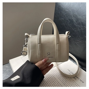 Close-up of mini cream Boston bag featuring lychee grain texture and brand logo detail