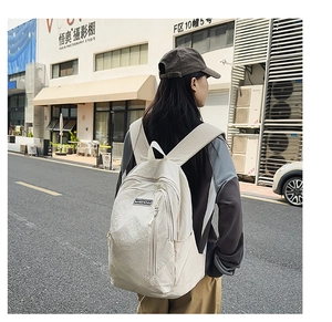 Outdoor street view of a woman wearing a minimalist off-white canvas backpack with front pocket